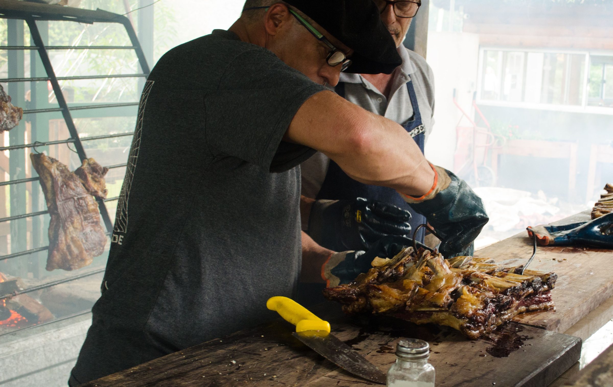 Pitmasters carving smoked ribs beside a wood-fired pit